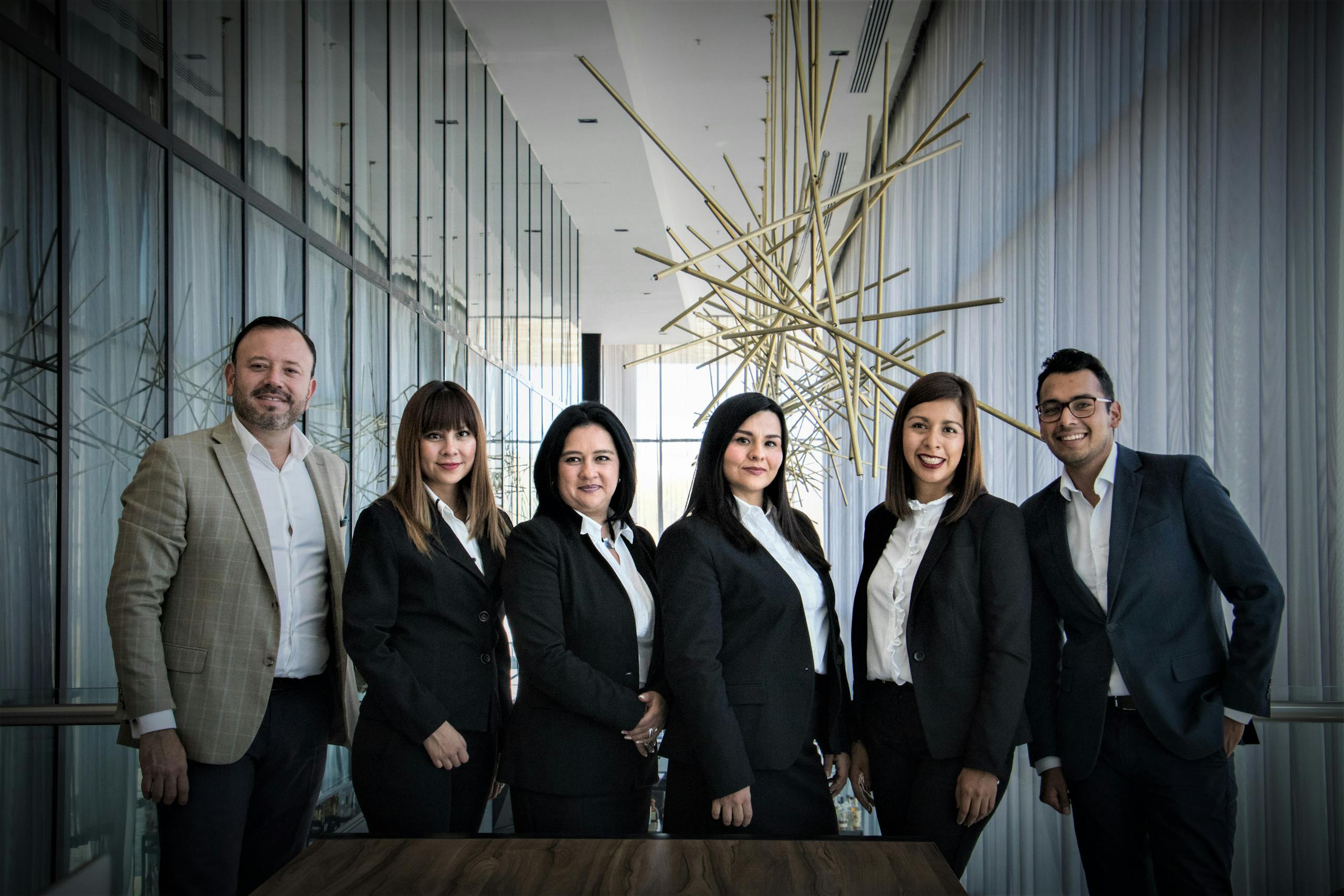 Diverse business team in formal attire posed in modern office.