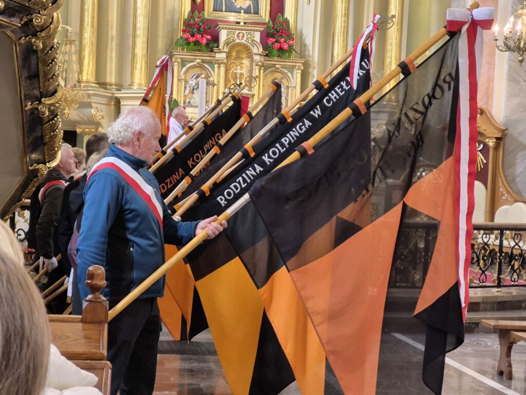 zdjęcie przedstawia grupę dorosłych osób ze sztandarami organizacji "Kolping" podczas uroczystego poświęcenia Kolpingowskiej Drogi Refleksji w Makowie Podhalańskim