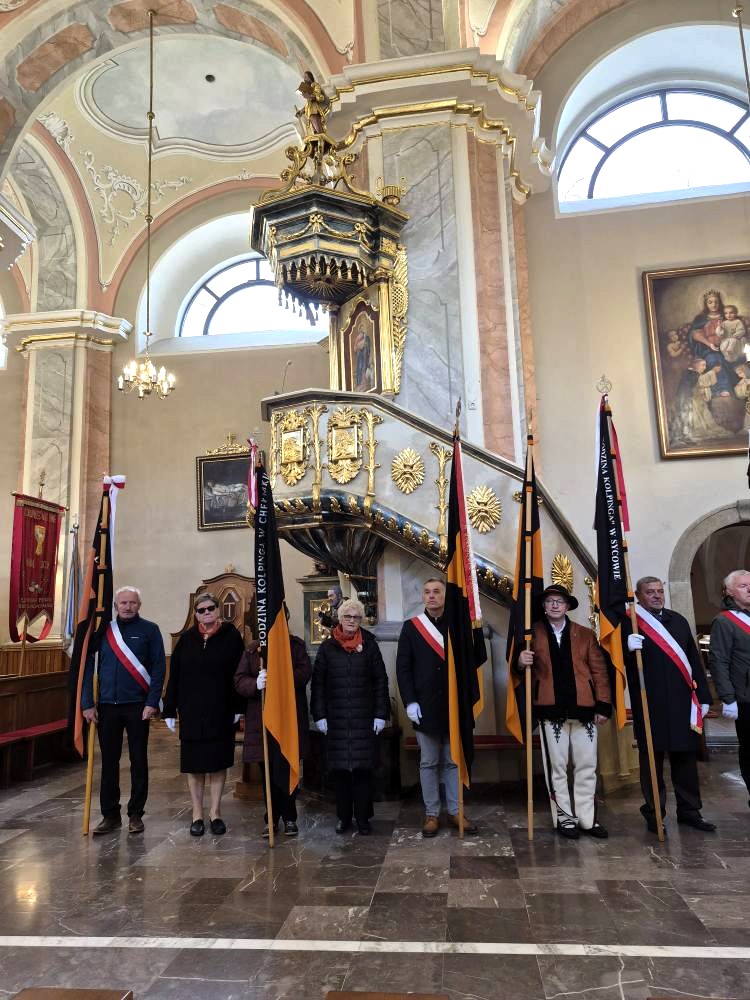 zdjęcie przedstawia grupę dorosłych osób ze sztandarami organizacji "Kolping" podczas uroczystego poświęcenia Kolpingowskiej Drogi Refleksji w Makowie Podhalańskim
