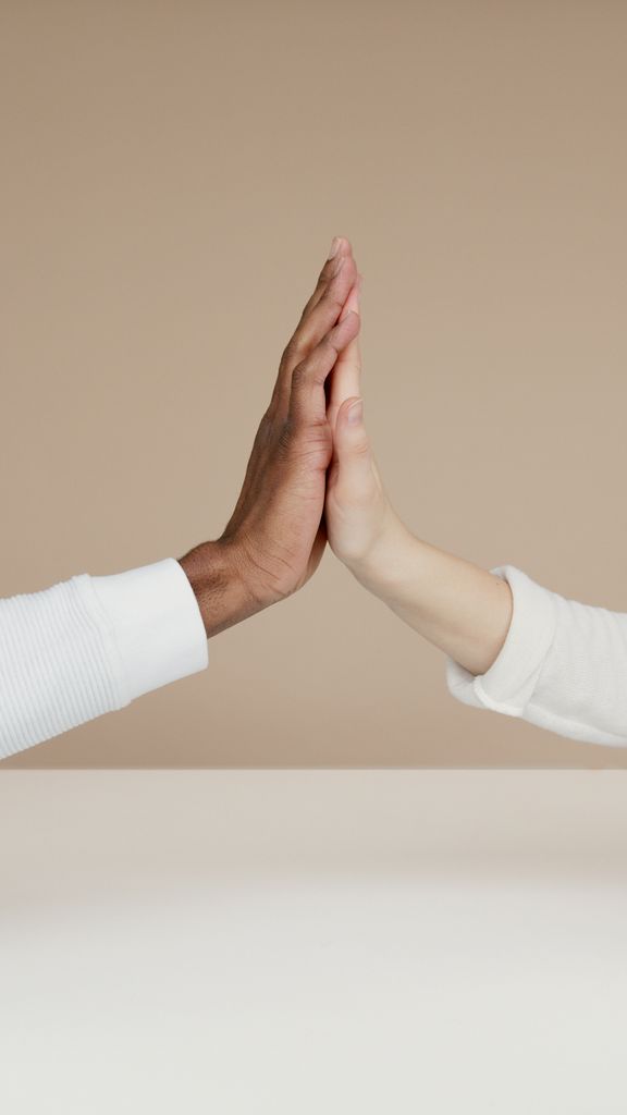 Two hands meet in a high-five, symbolizing cooperation and unity.