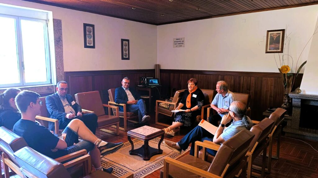 Uczestnicy Zgromadzenia Kontynentalnego Kolping Europa siedzą w kręgu w sali konferencyjnej i biorą udział w moderowanej dyskusji. Na środku ustawiono niewielki stolik, a spotkanie odbywa się w kameralnej atmosferze sprzyjającej wymianie doświadczeń.